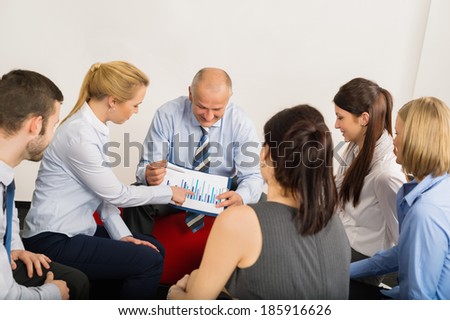 Business team discussing analysis graph sitting in meeting room