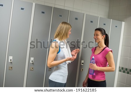 Happy fit women talking in locker room at gym