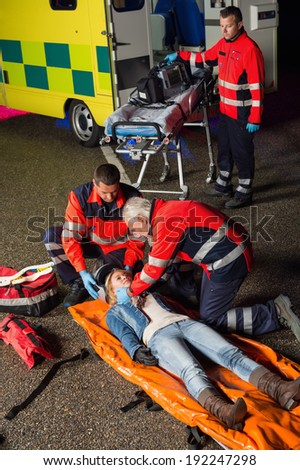 Emergency team helping injured motorcycle woman driver at night