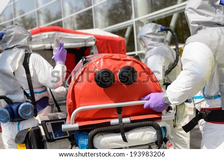 Biohazard medical team pushing stretcher towards decontamination chamber