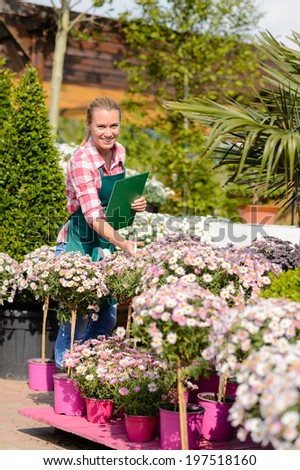 Happy woman make inventory potted flowers at garden shopping center