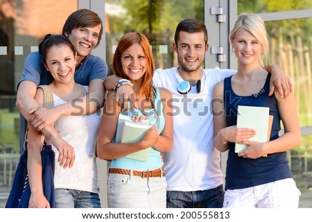 Group of smiling students standing front of college campus summer