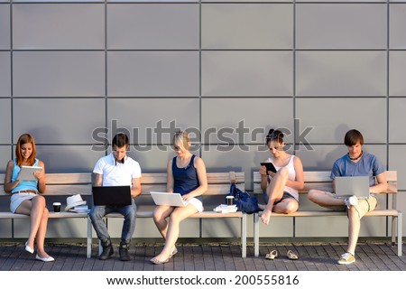College students internet computer addiction sitting bench outside campus summer