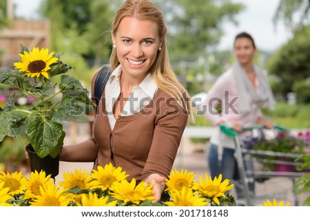 Smiling customer woman hold potted sunflower in garden center