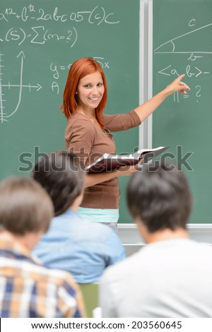 Mathematics student girl pointing on chalkboard looking at classmates