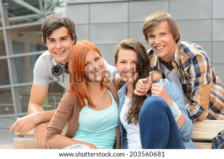 Cheerful group of student friends hugging together outside college