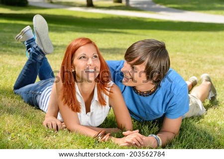 Teenage couple lying on grass laughing together enjoy summer day