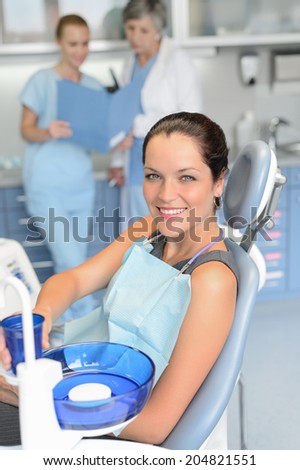 Woman patient sitting chair dental surgery checkup professional dentist team background