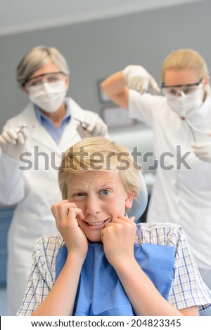 Scared teenage boy at dental surgery dentist woman with assistant
