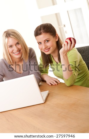 Two smiling girls watching laptop