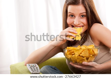 Young woman eating potato chips in front of TV