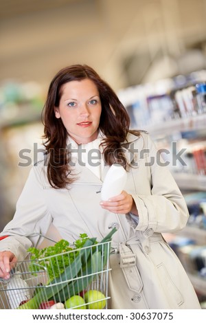 Shopping series - Young woman buying shampoo and holding shopping basket