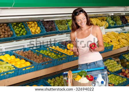 Grocery store - Woman holding two peppers, yellow and red