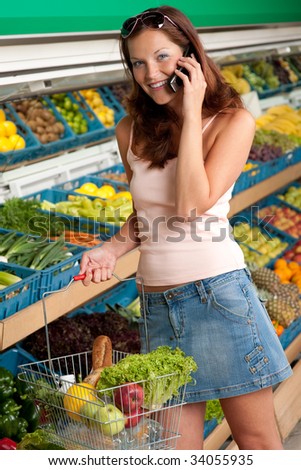 Grocery store - Smiling woman with mobile phone in a supermarket