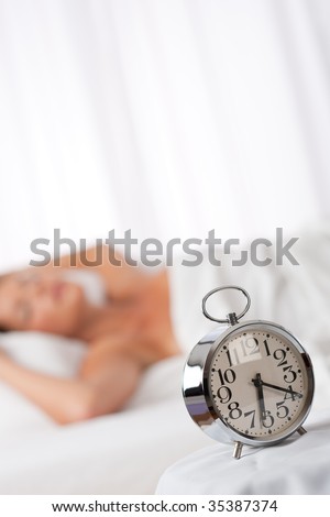 Silver alarm clock, woman in background, shallow DOF