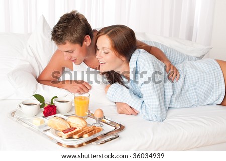 Happy man and woman having luxury hotel breakfast in bed together