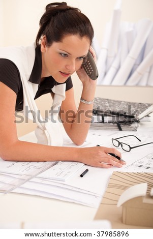 Female architect busy at the office calling and holding pen
