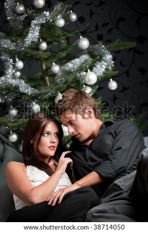 Extravagant man and woman in front of Christmas tree and black wallpaper
