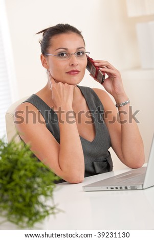 Modern professional businesswoman on the phone sitting at the office