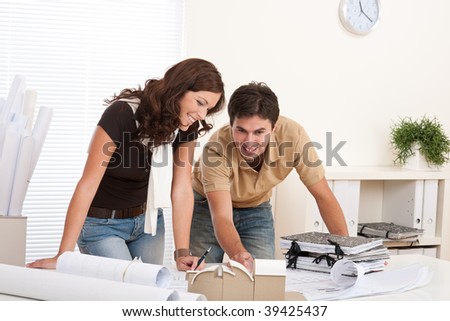 Young man and woman working at architect office with architectural model