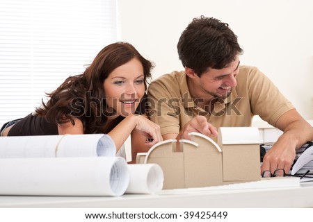 Smiling man and woman with architectural model at office
