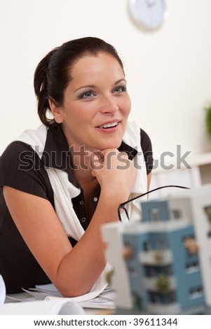 Portrait of female architect with architectural model in modern office