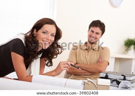 Smiling man and woman with architectural model at office