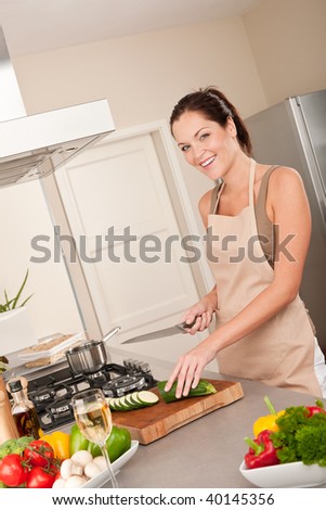 Young smiling woman cutting zucchini in the kitchen