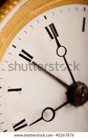 Close-up of antique white and gold clock with Roman numeral, macro lens