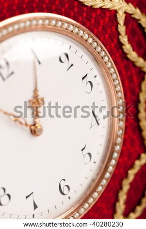 Close-up of red and gold antique tambour clock with Arabic numeral, macro lens