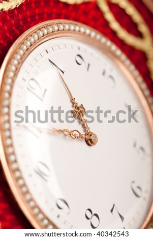 Close-up of red and gold antique tambour clock with Arabic numeral, macro lens