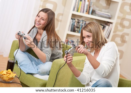 Students - Two female teenager playing video TV game in modern living room