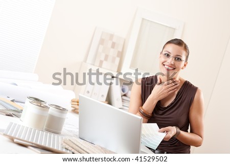 Smiling interior designer with color swatch and paint at office