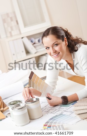 Young female interior designer at office with paint and color swatch