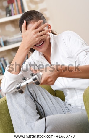 Students - Female teenager playing video game holding game pad in living room