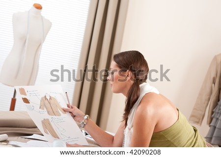 Fashion designer working at studio with dressmakers model and sketches