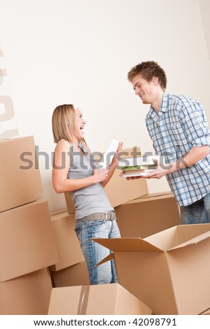 New house: Young couple with box in new home unpacking book