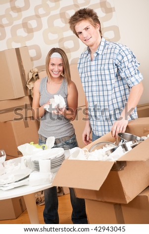 Moving house: Young couple unpacking kitchen dishes, pots, pans, in new home