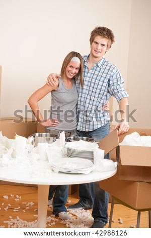 Moving house: Happy man and woman with box and dishes in new home