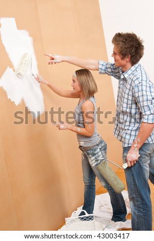 Home improvement: Young man and woman painting wall with paint roller