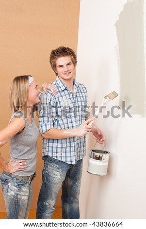 Home improvement: Man painting wall with paintbrush holding paint can