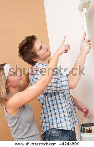 Home improvement: Man painting wall with paintbrush holding paint can