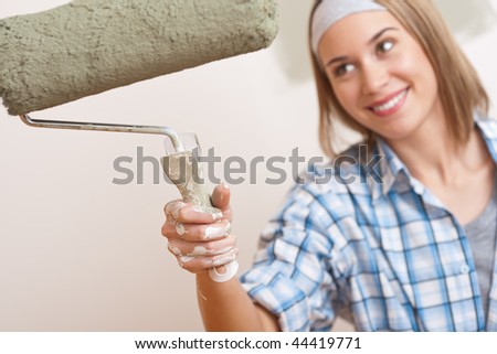 Home improvement: Young woman with paint roller painting wall