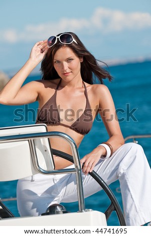 Young woman sailing on luxury yacht sunbathing in bikini