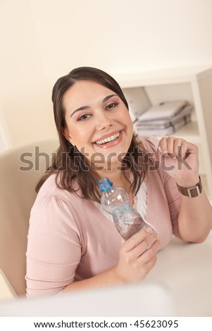 Young executive woman with bottle of water at office having break for drink