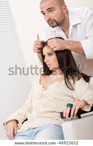 Professional male hairdresser comb female customer at salon, looking into mirror