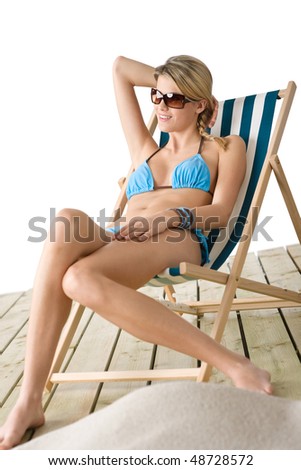 Beach - Young woman in bikini sitting on deck chair relaxing