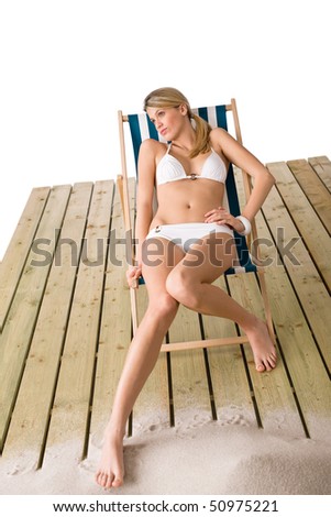 Beach - Woman in white bikini sunbathing on deck chair with sand