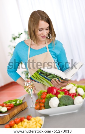Cooking - Woman reading cookbook for recipe in modern kitchen with vegetable and pasta