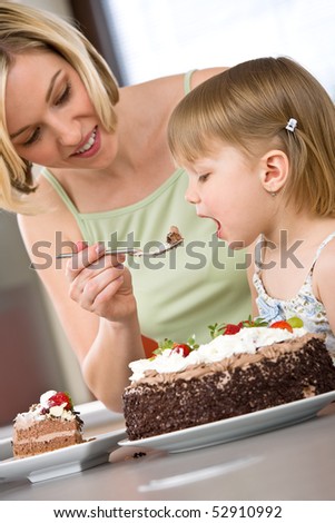 Mother and child tasting chocolate cake in modern kitchen